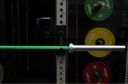 Barbell with green bar and colorful weight plates on a weight rack.
