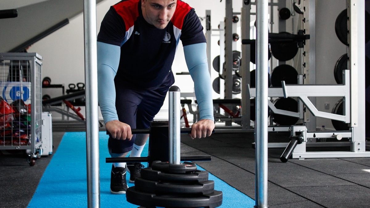 Person pushing weighted sled in sports clubs 